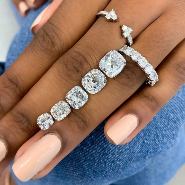 loose cushion diamonds on a ladies hand with jewelry