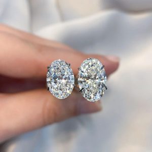 two oval cut diamonds held by tweezers ladies hand